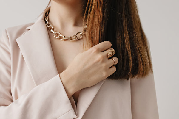 Woman showcasing matching gold necklace and ring set